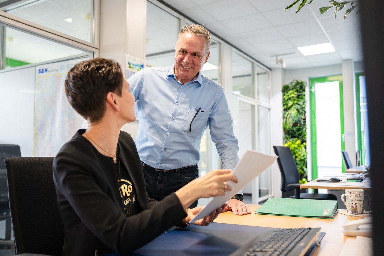 Zwei Kollegen besprechen Dokumente in einem modernen Büro.